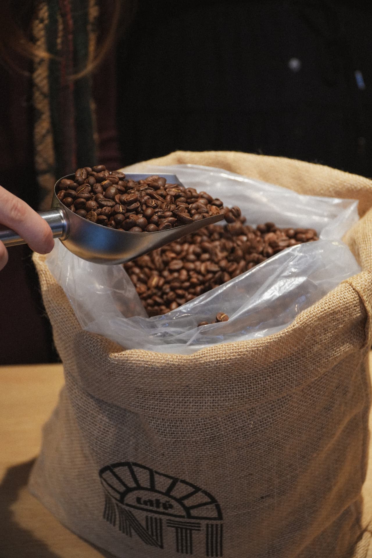 Scooping INTI coffee beans from a jute sack